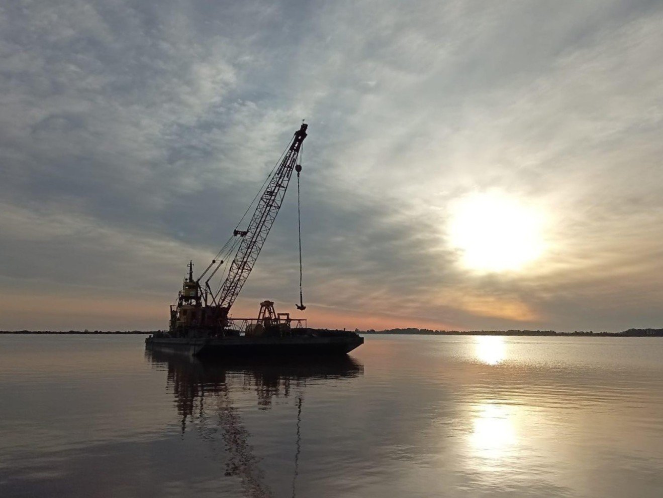 Imagen del puerto de yates de Juan Lacaze, con embarcación con grúa a contraluz.